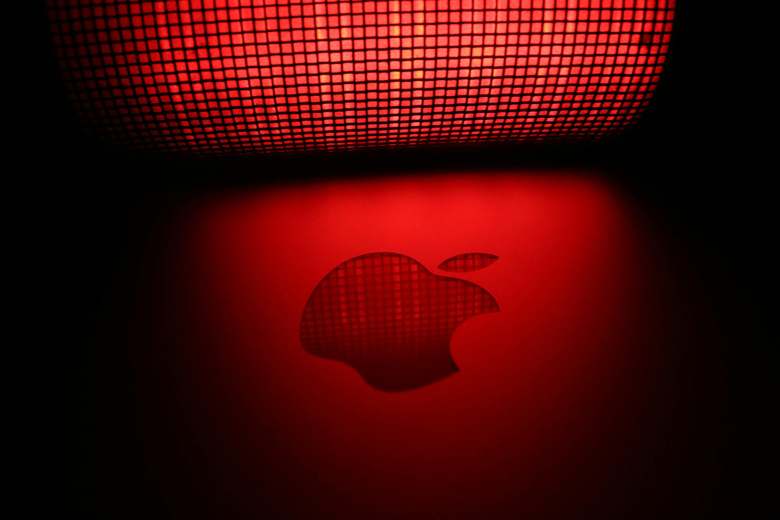 Artistic photo of a glowing apple-shaped graphic with a checkered pattern and red background.